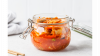 Glass jar containing kimchi sits on a white counter
