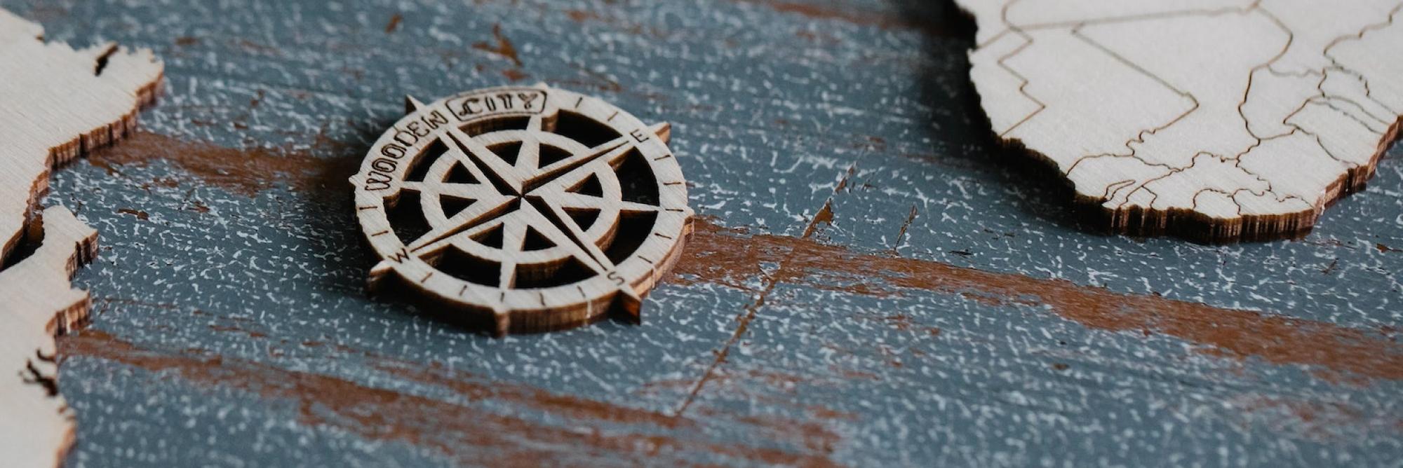 A wooden compass rose sits on a world map