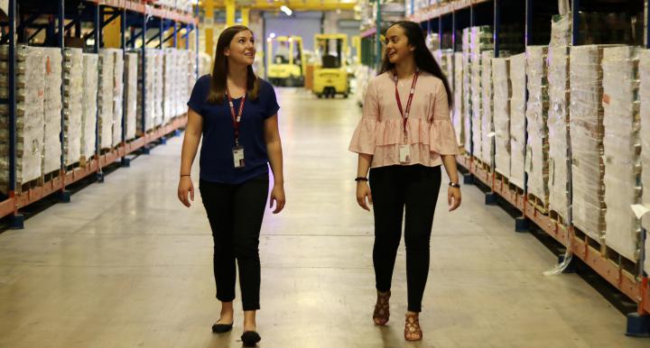 Two female students walk through food bank storage warehouse